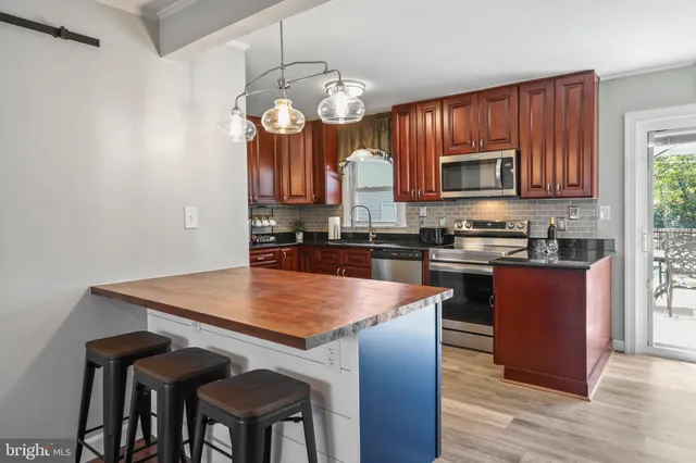 a kitchen with stainless steel appliances granite countertop a stove top oven a refrigerator a sink and a dining table with wooden floor