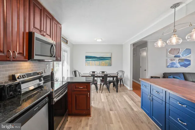 a kitchen with granite countertop a stove a sink a dining table and chairs
