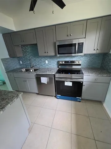 a kitchen with stainless steel appliances granite countertop a stove a sink and a microwave