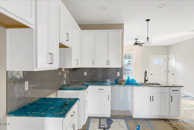 a kitchen with granite countertop a white cabinets and window