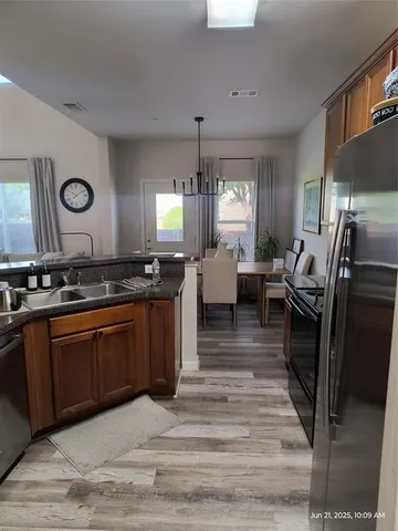 a kitchen with stainless steel appliances granite countertop a stove top oven a sink dishwasher a dining table and chairs with wooden floor