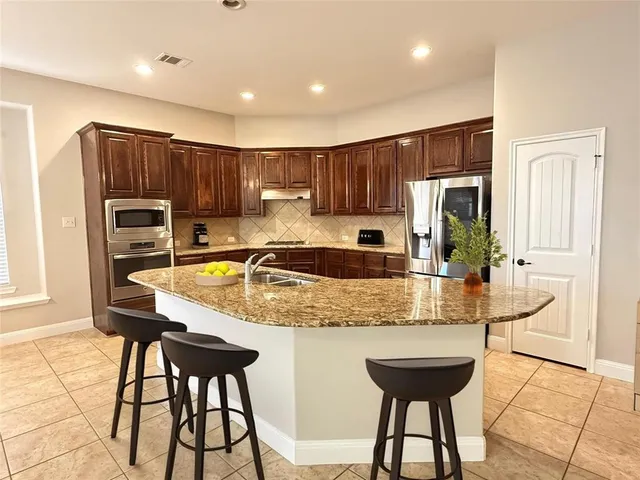a kitchen with kitchen island granite countertop wooden cabinets and a refrigerator