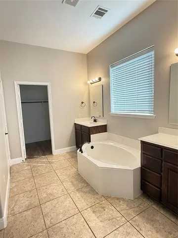 a bathroom with a tub a rug a window and a shower