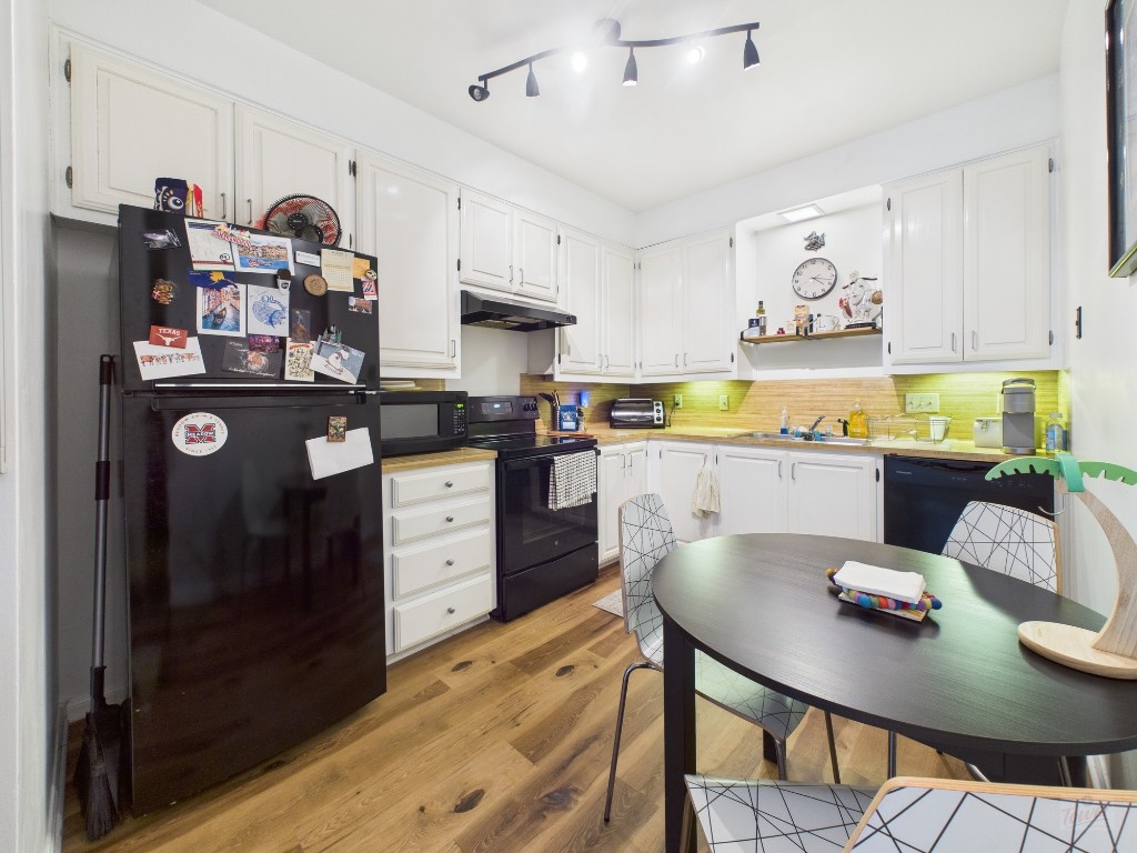 2529 Rio Grande Street, Unit 24 Austin, TX 78705 - Photo 5 of 15 a open kitchen with stainless steel appliances granite countertop a stove top oven a sink a dining table and chairs with wooden floor