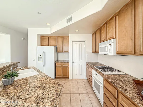 a kitchen with stainless steel appliances granite countertop a refrigerator and a stove top oven