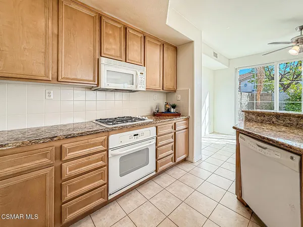 a kitchen with granite countertop white cabinets and white appliances