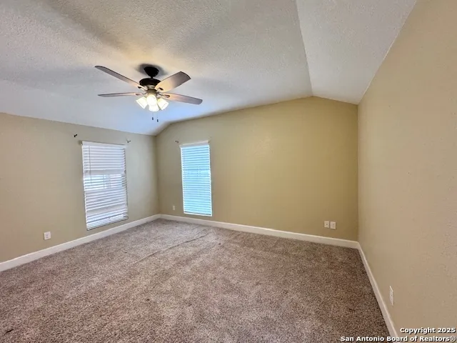 an empty room with windows and chandelier fan