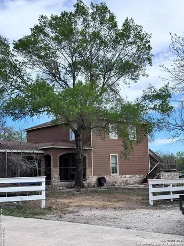 a front view of a house with a tree