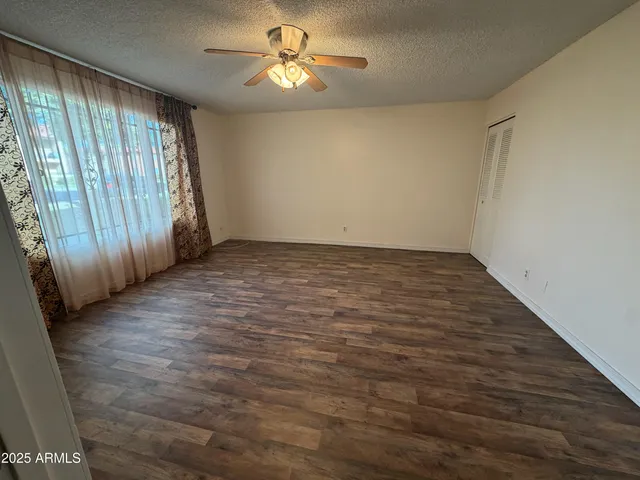 an empty room with wooden floor fan and windows