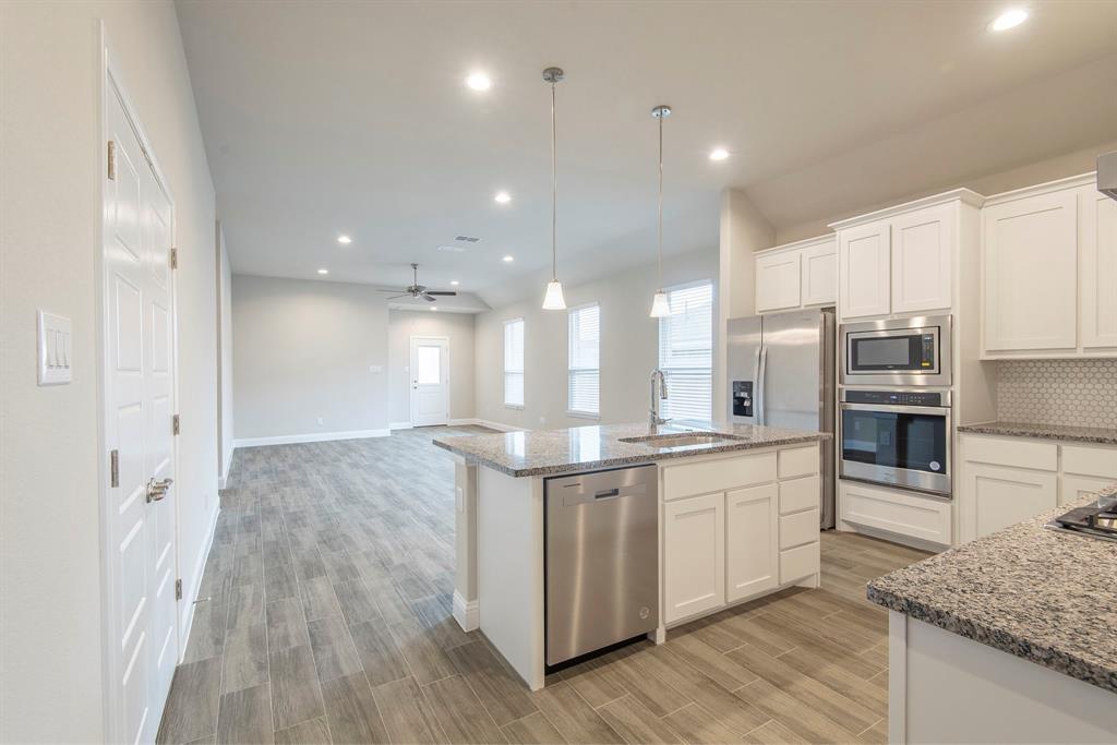 2301 Ruff Road Denton, TX 76205 - Photo 3 of 23 Modern kitchen featuring an island with a stainless steel dishwasher and undermount sink, granite countertops, white cabinetry, and stainless steel built-in appliances