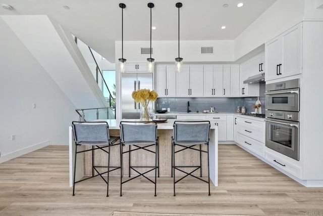 a kitchen with stainless steel appliances kitchen island granite countertop a dining table chairs and sink