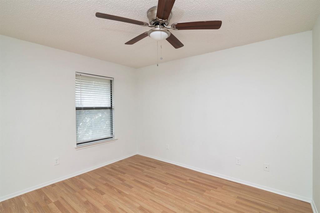 1445 Weiler Boulevard, Unit 1431 Fort Worth, TX 76112 - Photo 12 of 15 an empty room with wooden floor fan and windows