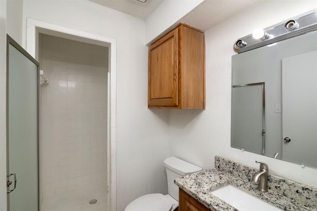 1445 Weiler Boulevard, Unit 1431 Fort Worth, TX 76112 - Photo 14 of 15 a bathroom with a granite countertop sink a toilet and shower