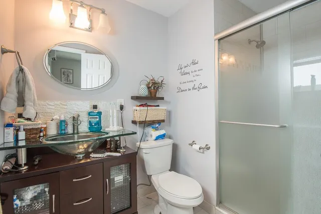 a bathroom with a granite countertop toilet a sink and a mirror
