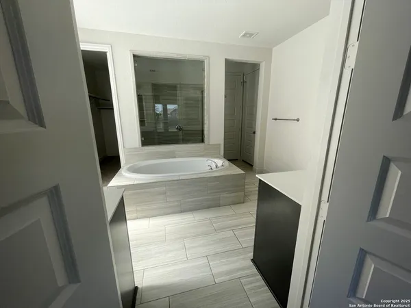 a large bathroom with a tub sink and mirror