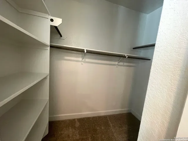 a view of a large pool with lawn chairs under an umbrella