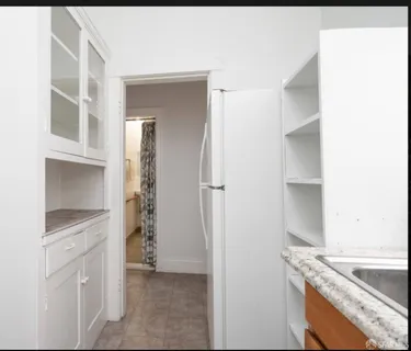 a kitchen with white cabinets and refrigerator