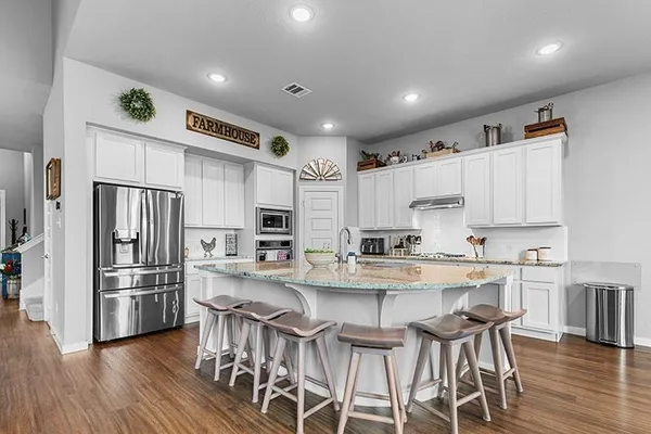a kitchen with stainless steel appliances a sink a stove a refrigerator with wooden floor and cabinets