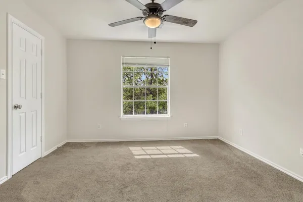 an empty room with a window and a chandelier fan
