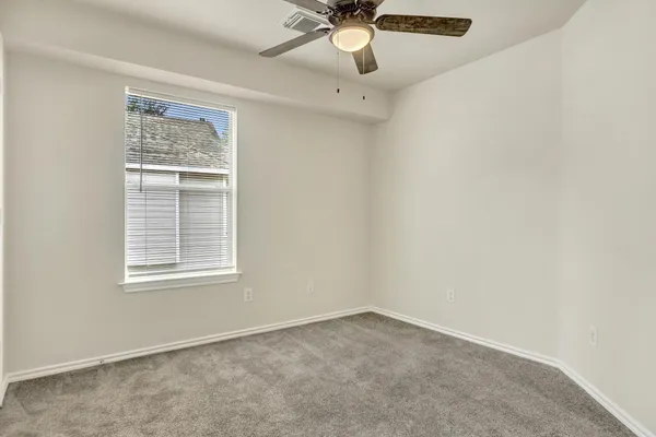 an empty room with a window and a fan