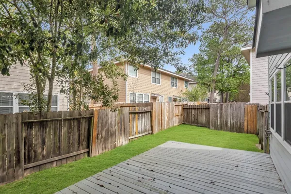 a view of a backyard with wooden fence and large trees