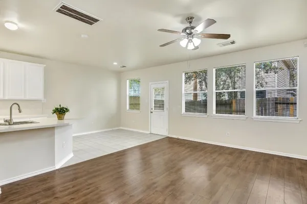 a view of an empty room with a window and wooden floor