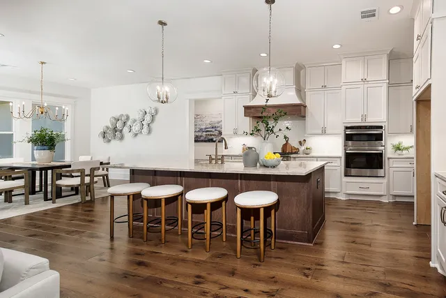 a kitchen with stainless steel appliances granite countertop a sink a stove a dining table and chairs