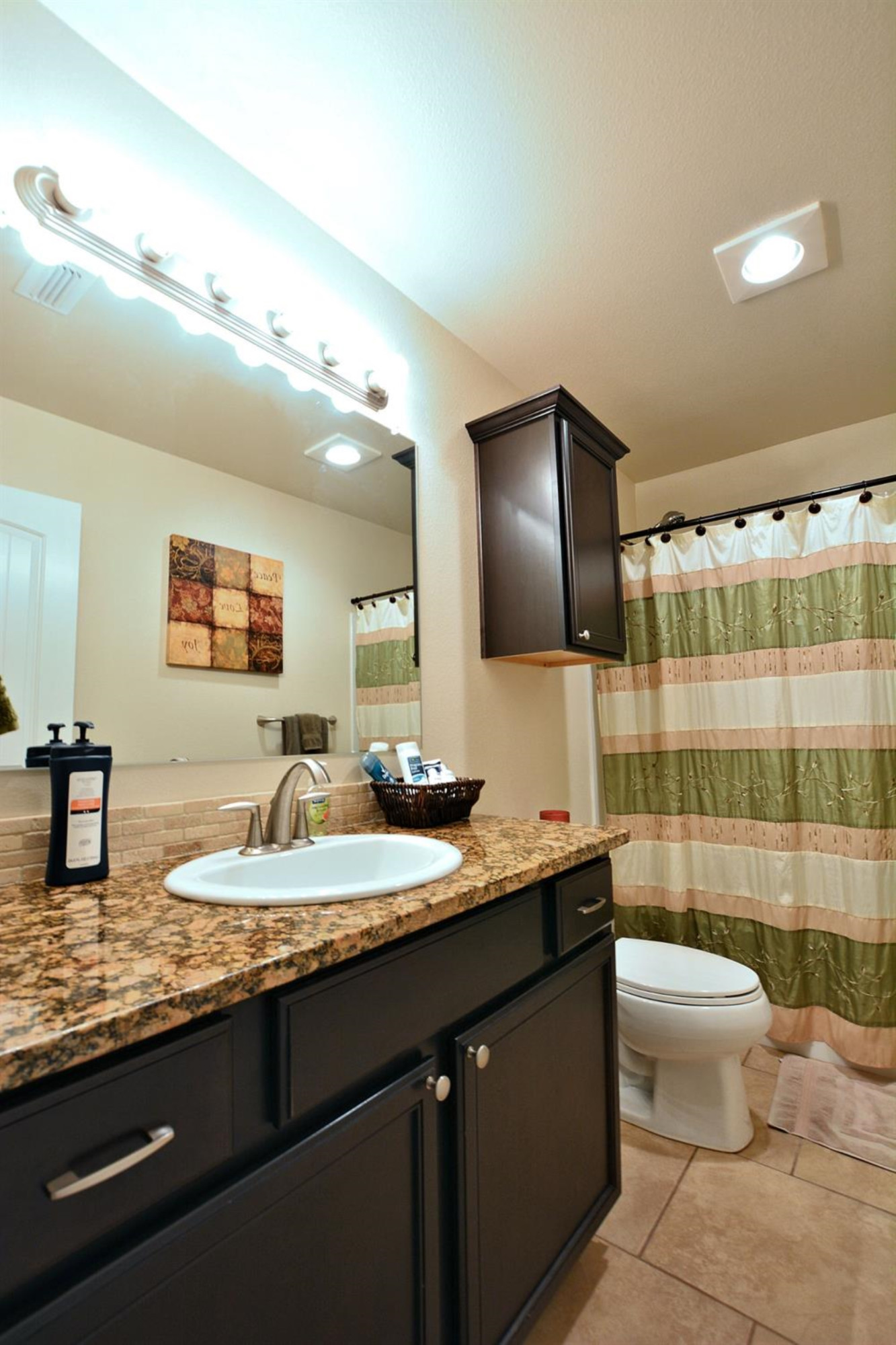 3703 Rochester Avenue Lubbock, TX 79407 - Photo 17 of 20 a bathroom with a granite countertop sink a toilet a mirror and shower curtain