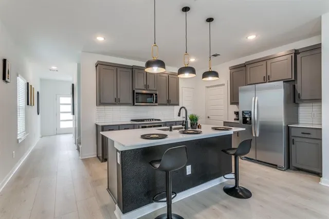 a kitchen with stainless steel appliances granite countertop a stove a refrigerator a sink and a oven