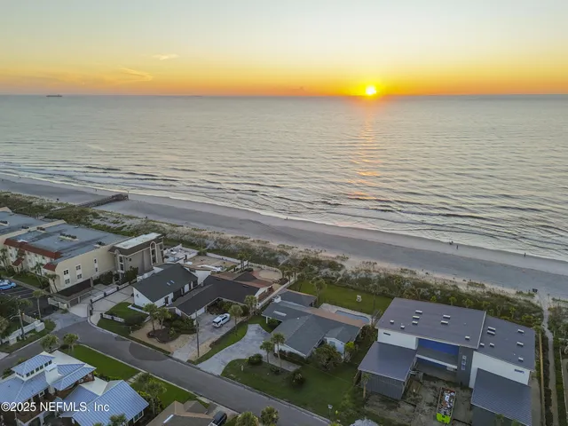 an aerial view of ocean and residential houses with outdoor space