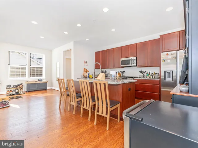 a kitchen with stainless steel appliances a table chairs refrigerator and a sink