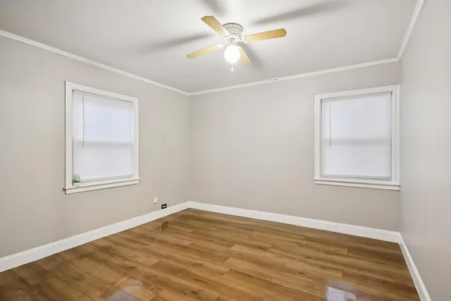 a view of empty room with wooden floor and fan