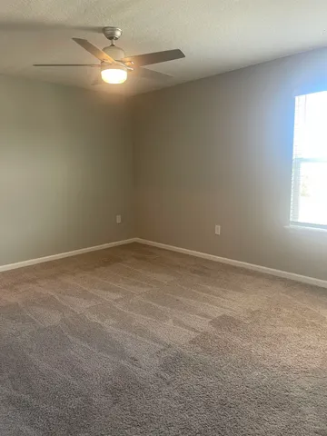 an empty room with a window and ceiling fan