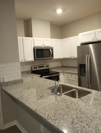 a kitchen with a sink a counter top space cabinets and stainless steel appliances