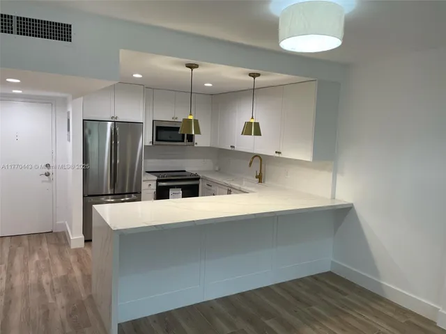 a large kitchen with stainless steel appliances a large counter top a stove a refrigerator and a sink