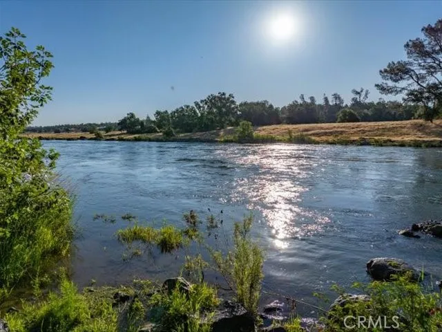 a view of a lake with lawn chairs and large trees