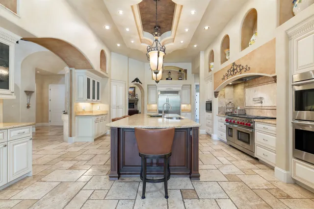 a kitchen with stainless steel appliances granite countertop a stove a sink dishwasher a dining table and chairs with wooden floor