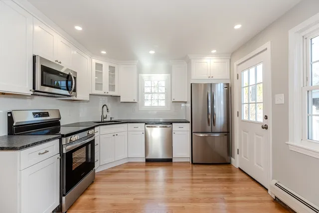 a kitchen with stainless steel appliances granite countertop a refrigerator a stove top oven a sink and dishwasher with wooden floor