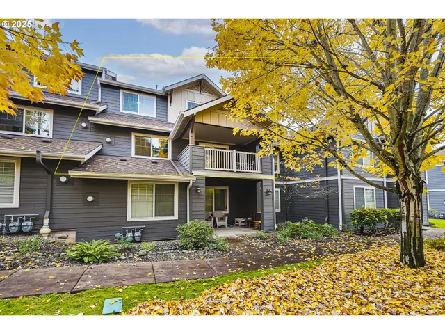 a view of a brick house with many windows plants and large tree