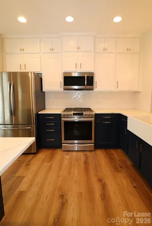 a kitchen with stainless steel appliances kitchen island a hardwood floor and a view of living room