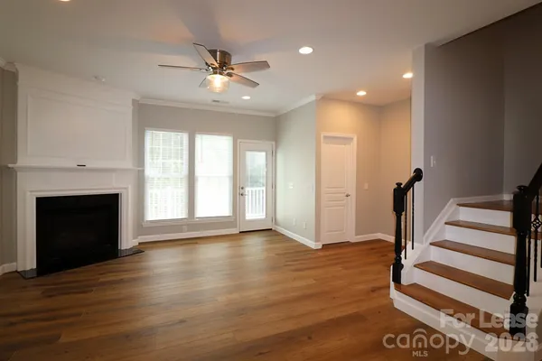 a view of an empty room with wooden floor fireplace and a window