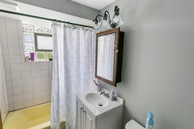 a bathroom with a sink vanity mirror and tub