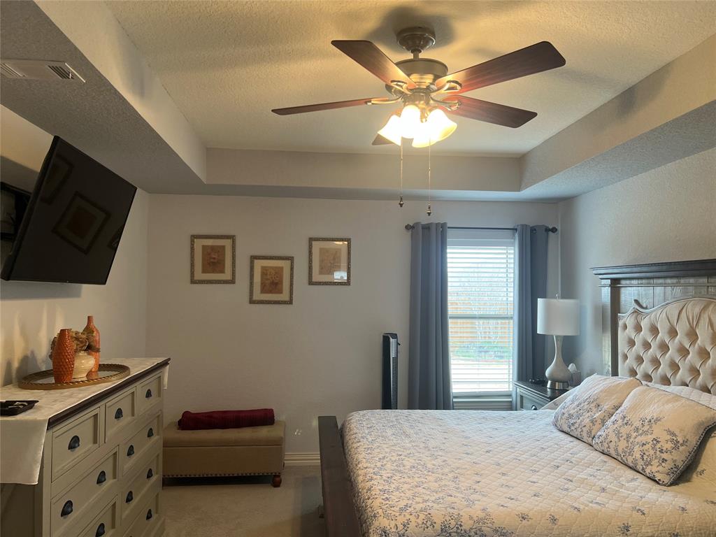 312 McAfee Street Mabank, TX 75147 - Photo 27 of 40 a bedroom with a bed and a flat tv screen on the dresser