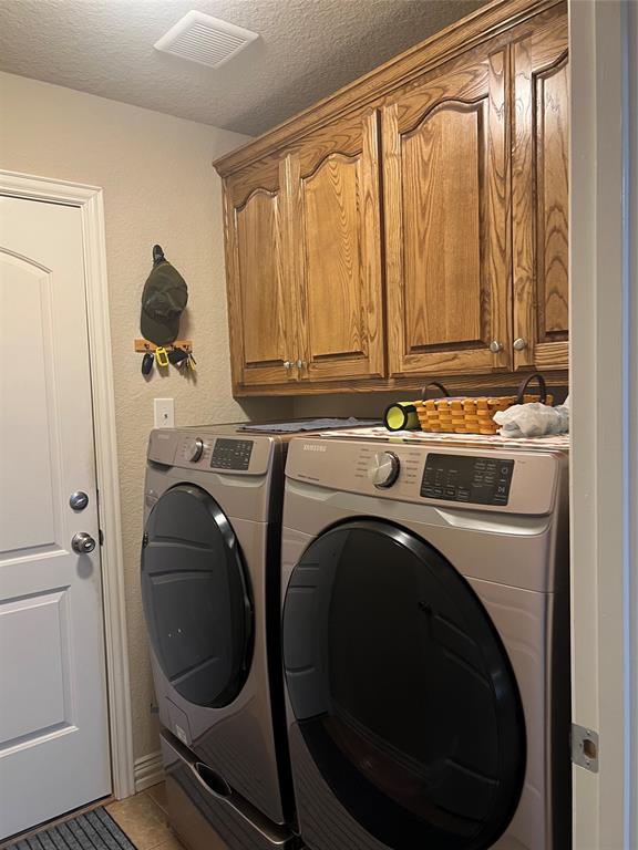 312 McAfee Street Mabank, TX 75147 - Photo 9 of 40 Laundry room with a textured ceiling, separate washer and dryer, cabinet space, and light tile patterned flooring