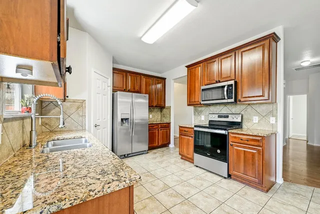 a kitchen with stainless steel appliances granite countertop a stove a sink and a microwave
