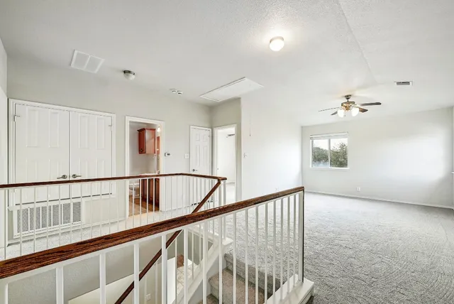 an empty room with wooden floor fan and windows