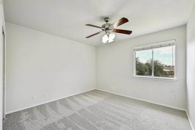 a view of an empty room with window and a ceiling fan