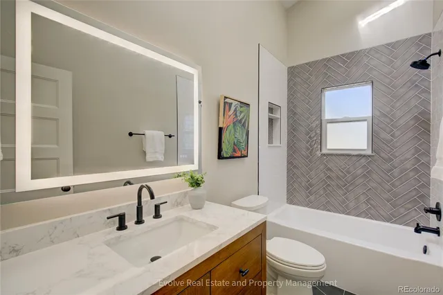 a bathroom with a sink a toilet a mirror a vanity a bathtub and shower