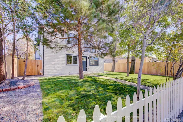a view of a backyard with wooden fence and a large tree