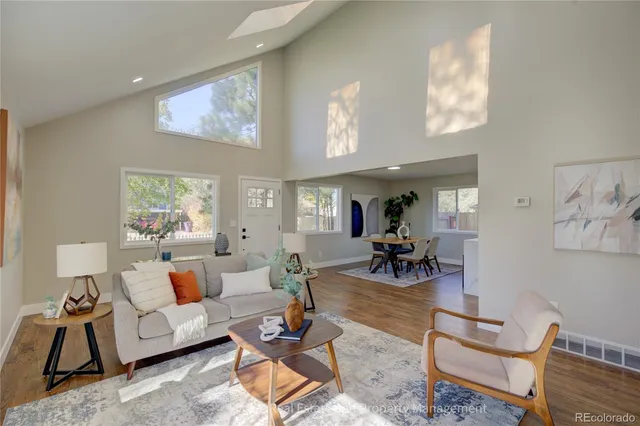 a living room with furniture and a dining table with wooden floor